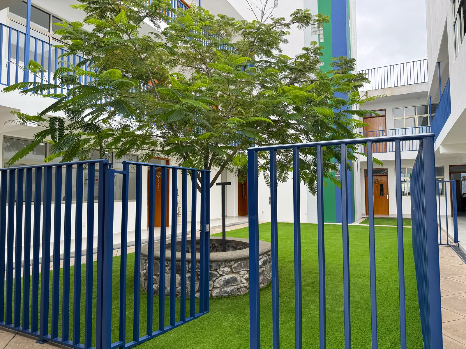 Patio central con árbol y reja azul