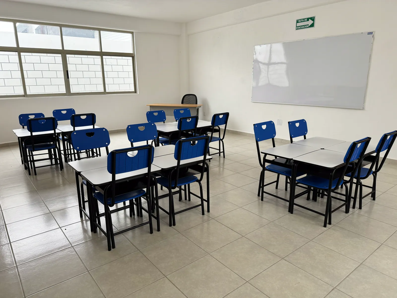 Salón con mesas de trabajo y pizarrón blanco