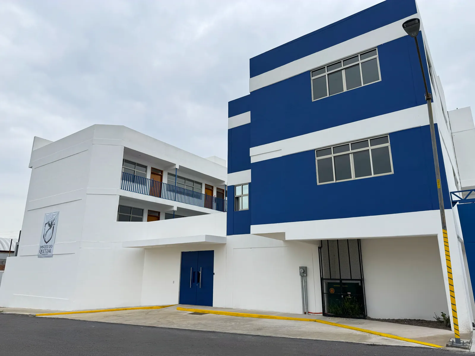 Edificio azul y blanco del Instituto Quetzal visto desde la esquina